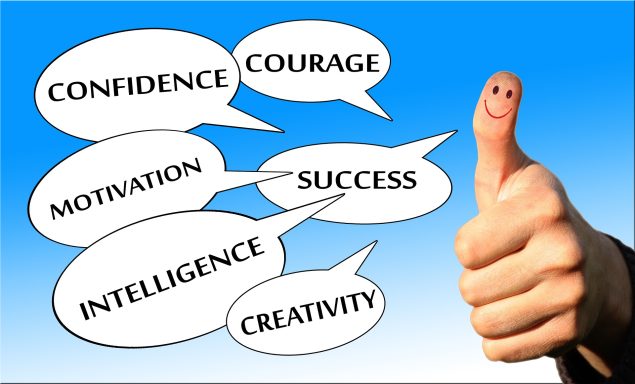 Main faisant un pouce levé entourée de bulles de mots positifs comme courage motivation et confiance